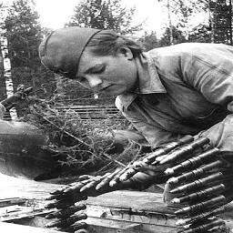 Стрелок-оружейник гв. ефрейтор Клавдия Данилова загружает боеприпасы к пушке ШВАК.
